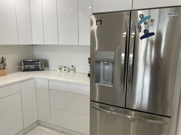 a kitchen with appliances a refrigerator and cabinets