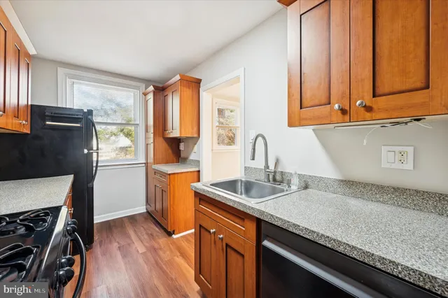 a kitchen with stainless steel appliances granite countertop a sink a refrigerator and wooden cabinets