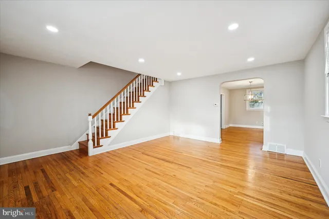 a view of an empty room with wooden floor and stairs