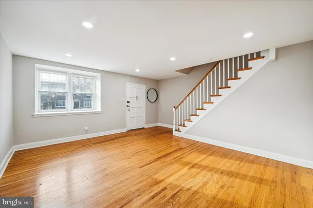 a view of an empty room with wooden floor and stairs