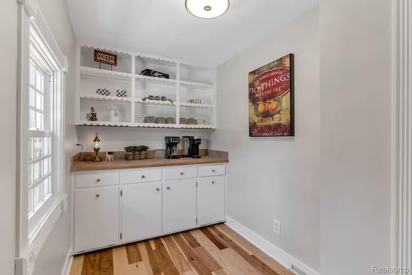 4567 North Seymour Road Flushing, MI 48433 - Photo 8 of 43 Built-in shelving with decorative scalloped trim, white base cabinetry with silver-tone hardware, wood-finish flooring, and a multi-pane window