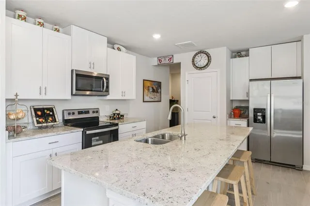 a kitchen with granite countertop a refrigerator stove microwave and sink