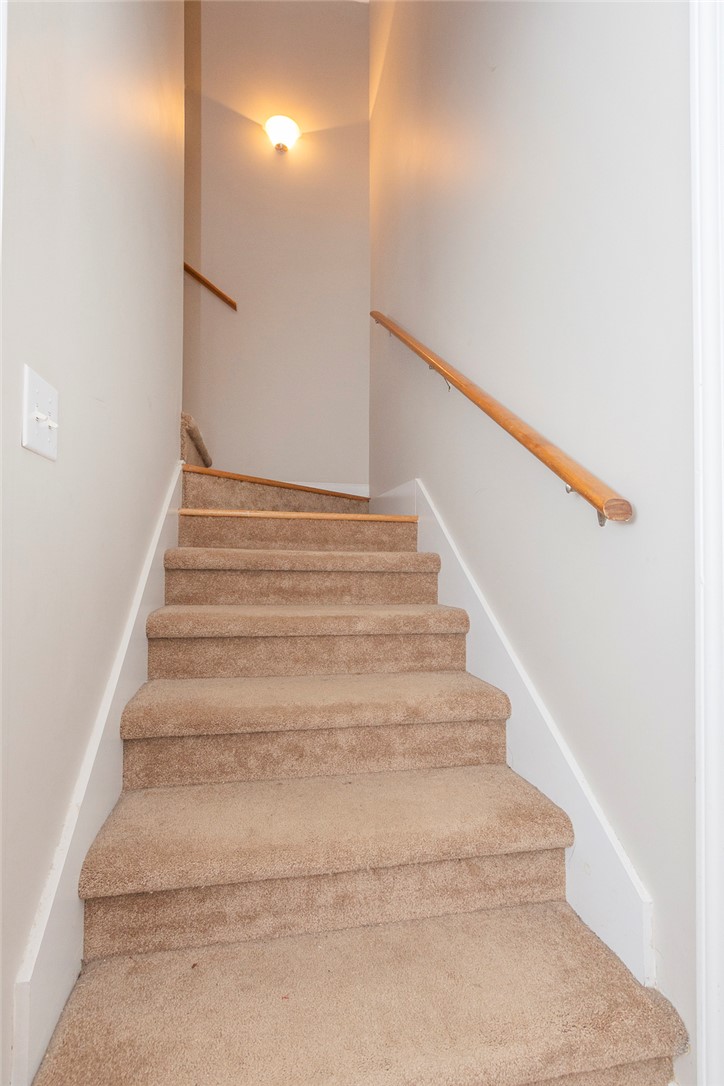 861 North Old Pendleton Road Liberty, SC 29657 - Photo 29 of 45 Carpeted stairs with a natural wood handrail lead to the upper level, illuminated by a warm light fixture.