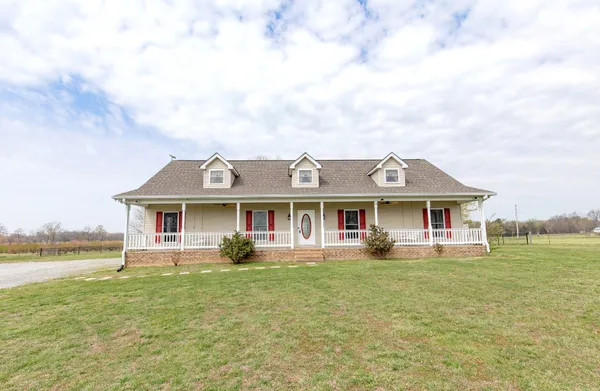 a front view of a house with a garden and lake view