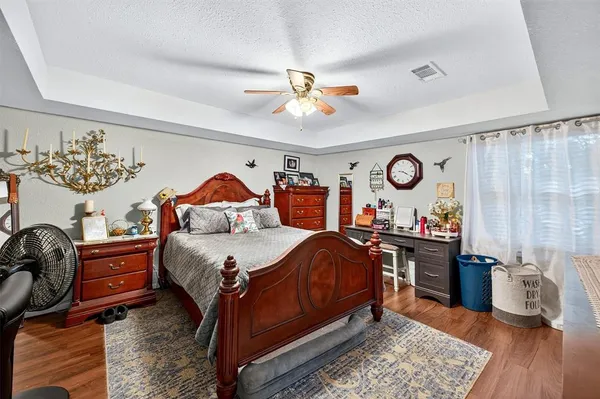 a bedroom with a bed and dresser with wooden floor