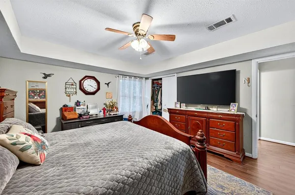 a bedroom with bed and a flat tv screen on dresser