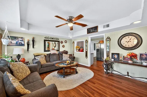 a living room with furniture a clock and a ceiling fan