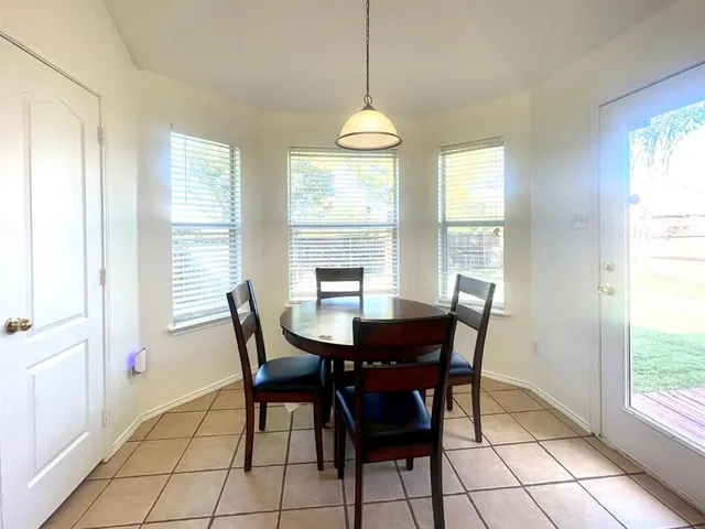 a kitchen with granite countertop a stove a sink a dining table and chairs