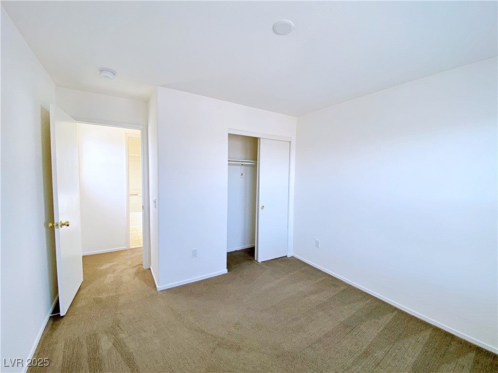 9335 Indian Corn Court, Unit 101 Las Vegas, NV 89178 - Photo 16 of 18 Unfurnished bedroom featuring carpet and a closet
