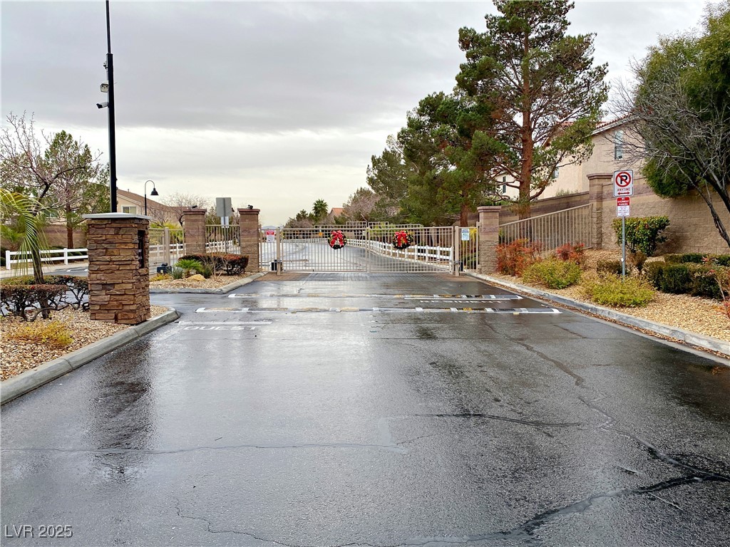 9335 Indian Corn Court, Unit 101 Las Vegas, NV 89178 - Photo 17 of 18 View of asphalt road with traffic signs, a gate, curbs, and a gated entry