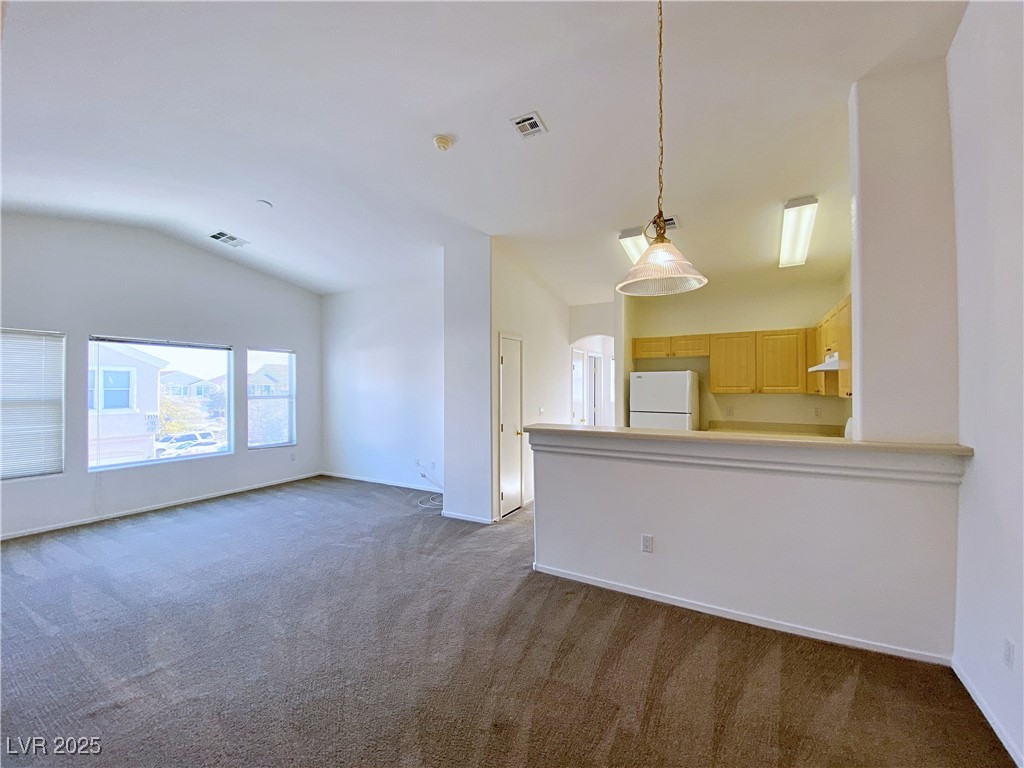 9335 Indian Corn Court, Unit 101 Las Vegas, NV 89178 - Photo 2 of 18 Unfurnished living room with lofted ceiling and dark carpet