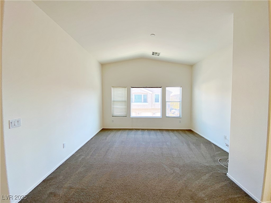 9335 Indian Corn Court, Unit 101 Las Vegas, NV 89178 - Photo 3 of 18 Empty room featuring carpet flooring and lofted ceiling