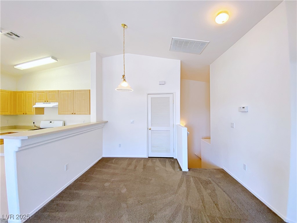 9335 Indian Corn Court, Unit 101 Las Vegas, NV 89178 - Photo 4 of 18 Kitchen with lofted ceiling, dark carpet, light brown cabinetry, decorative light fixtures, and a peninsula