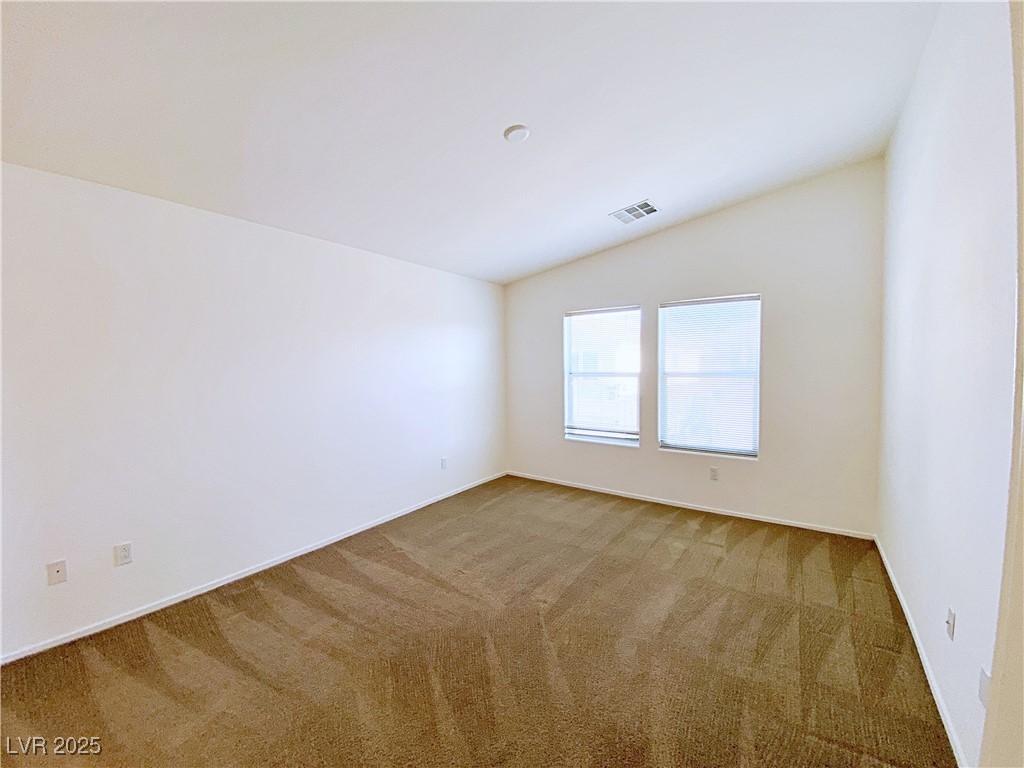 9335 Indian Corn Court, Unit 101 Las Vegas, NV 89178 - Photo 9 of 18 Spare room with light carpet and vaulted ceiling