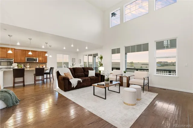 a kitchen with a stove center island wooden floor and a living room view