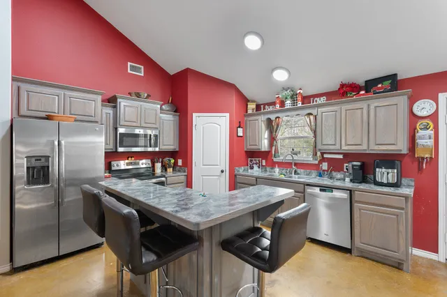a kitchen with granite countertop a sink stainless steel appliances and cabinets