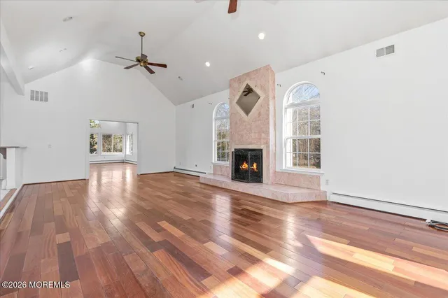 a view of an empty room with wooden floor fireplace and a window