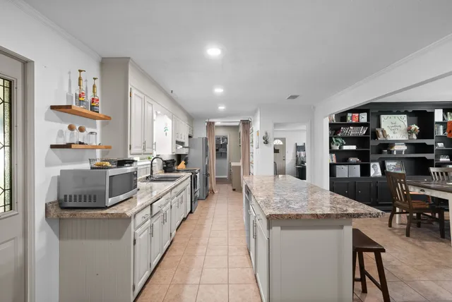 a large kitchen with kitchen island a large counter top stainless steel appliances and cabinets