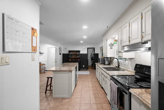 a kitchen with stainless steel appliances granite countertop a stove top oven a sink a refrigerator and white cabinets