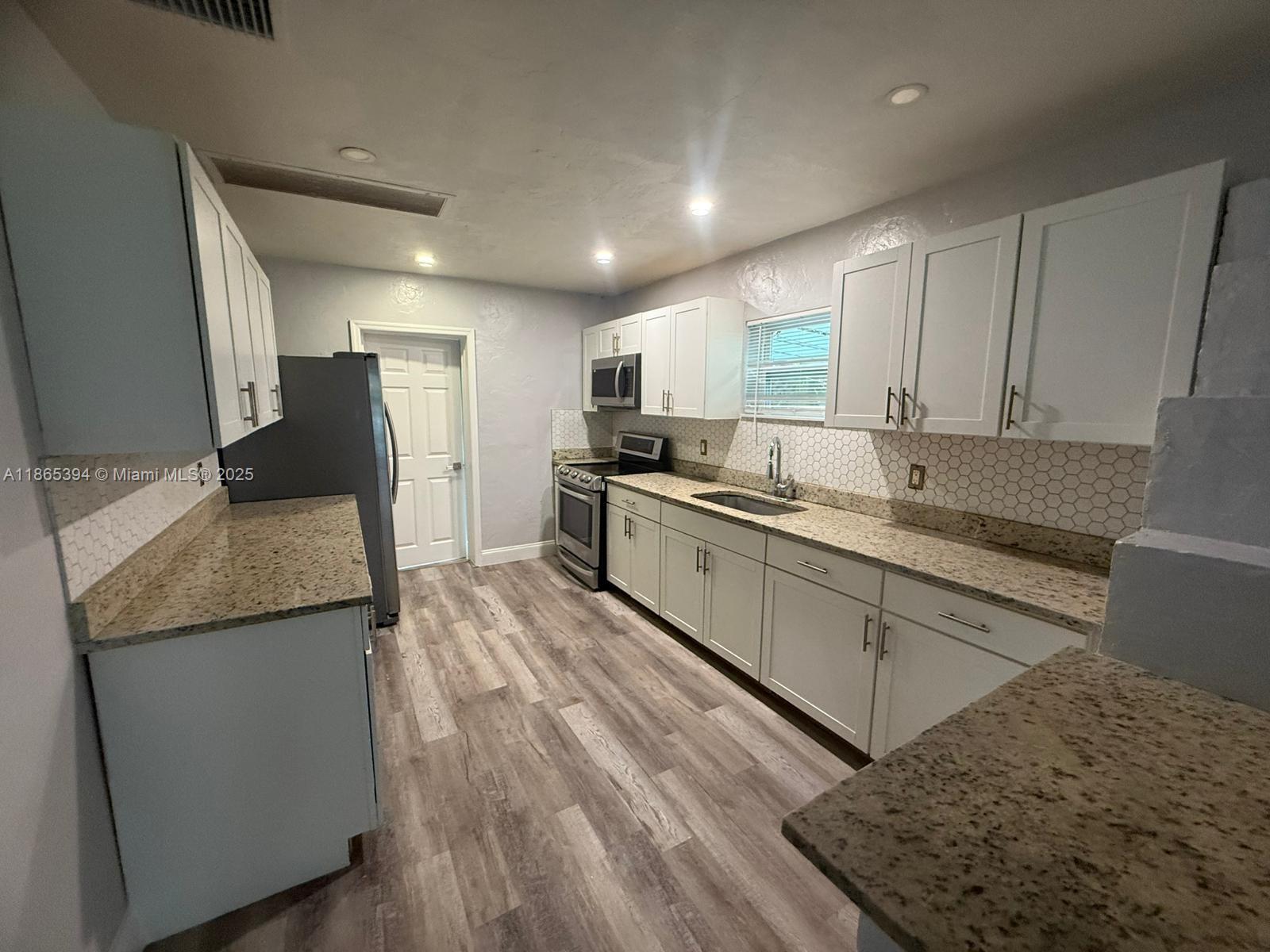 173 West 16th Street, Unit A Riviera Beach, FL 33404 - Photo 2 of 17 a kitchen with stainless steel appliances granite countertop a sink and a stove