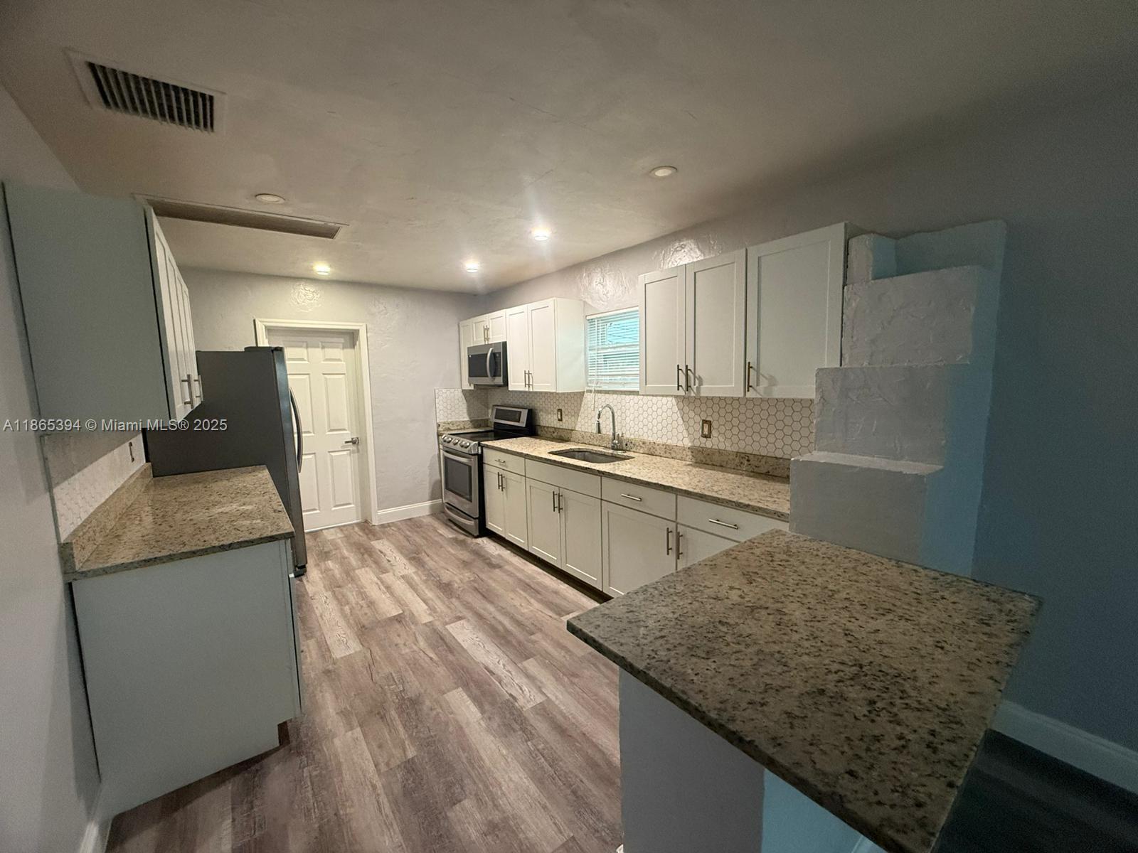 173 West 16th Street, Unit A Riviera Beach, FL 33404 - Photo 6 of 17 a kitchen with stainless steel appliances granite countertop a sink stove and refrigerator