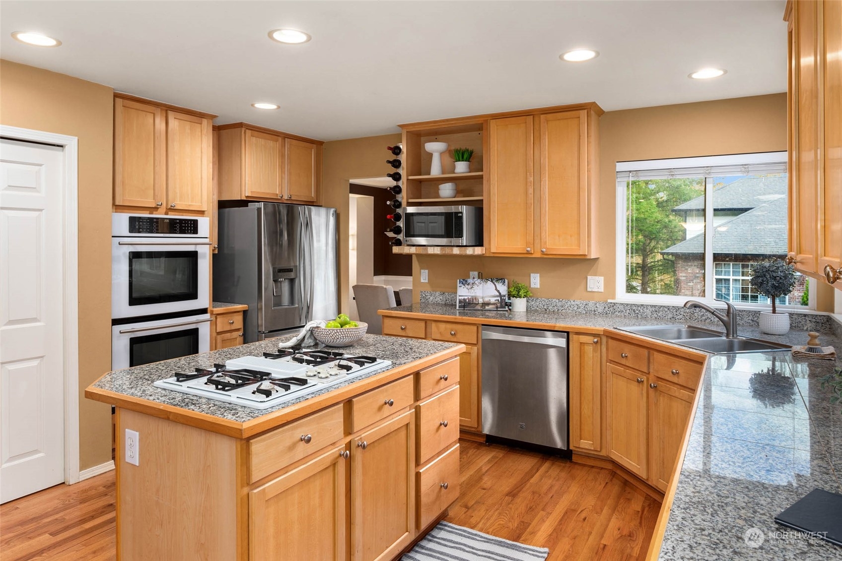 2710 236th Street Southeast Bothell, WA 98021 - Photo 6 of 30 a kitchen with stainless steel appliances a stove a sink dishwasher a refrigerator and wooden cabinets with wooden floor