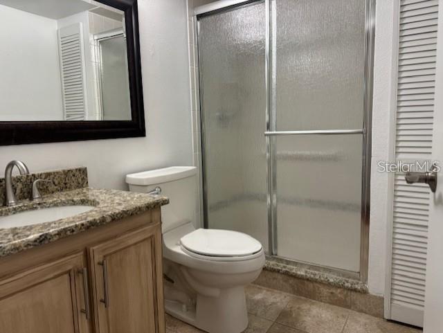 1261 Pine Ridge Circle West, Unit E2 Tarpon Springs, FL 34688 - Photo 12 of 16 a bathroom with a granite countertop toilet sink and mirror