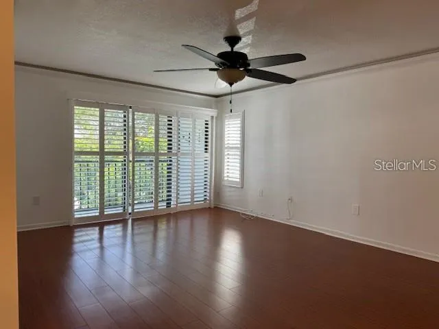 a view of an empty room with wooden floor and a window