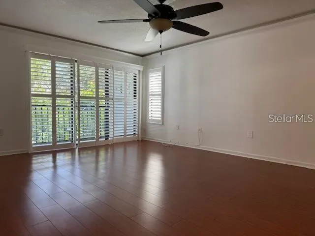 a view of an empty room with wooden floor and a window