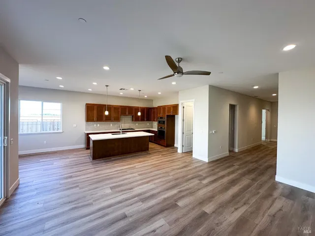 a large kitchen with stainless steel appliances a large counter top a sink a refrigerator and a window