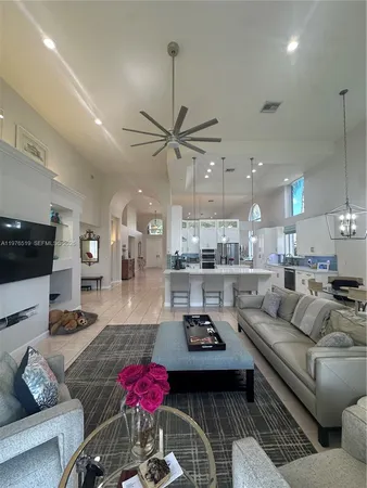 a living room with furniture kitchen view and a chandelier