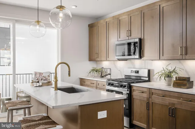 a kitchen with stainless steel appliances a sink a stove a microwave a sink a refrigerator and cabinets