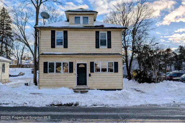 a front view of a house with a yard covered in snow