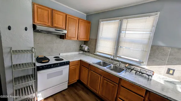 a kitchen with stainless steel appliances granite countertop a refrigerator a sink dishwasher a stove and white countertops with wooden floor