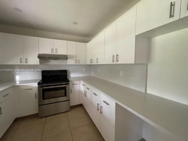 a kitchen with granite countertop white cabinets and stainless steel appliances