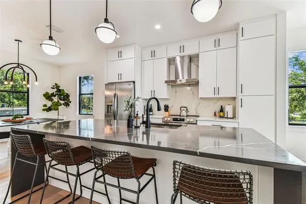 a kitchen with stainless steel appliances granite countertop a stove a sink dishwasher a refrigerator and microwave with wooden floor