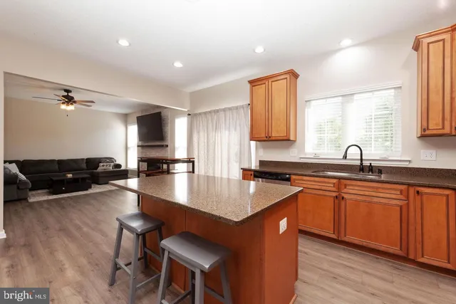 a open kitchen with stainless steel appliances granite countertop a sink dishwasher a stove a dining table and chairs with wooden floor