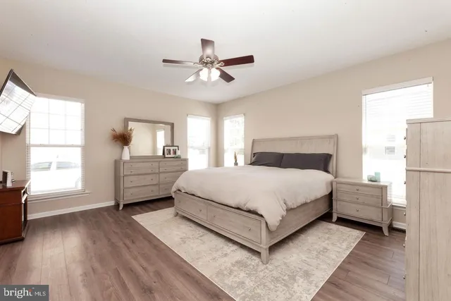a bedroom with a bed painting on wall and windows