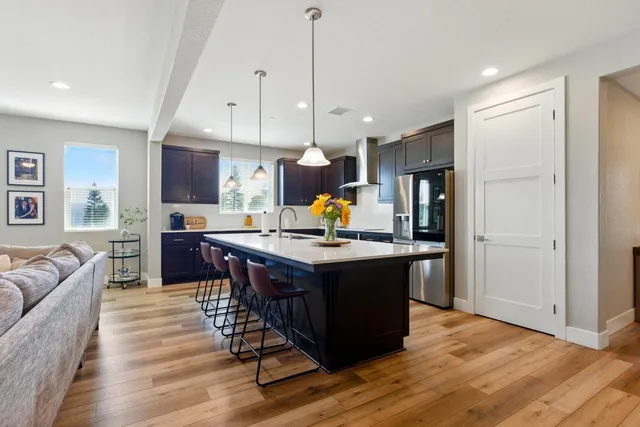 a living room with stainless steel appliances granite countertop furniture wooden floor and a view of kitchen