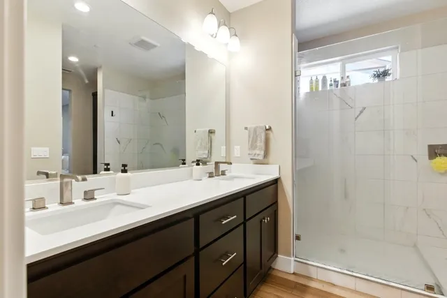 a bathroom with a double vanity sink mirror and shower