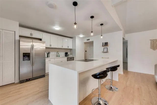 a kitchen with kitchen island a sink stainless steel appliances and wooden floor