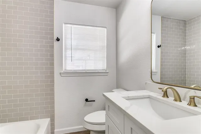 a bathroom with a sink toilet vanity and tub
