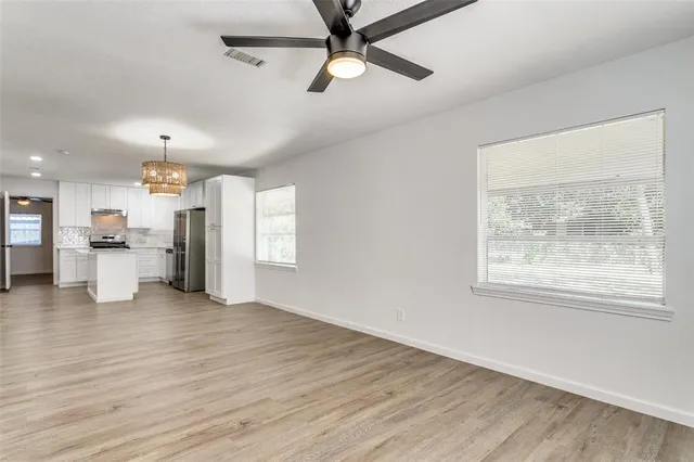 a view of an empty room with a window and wooden floor