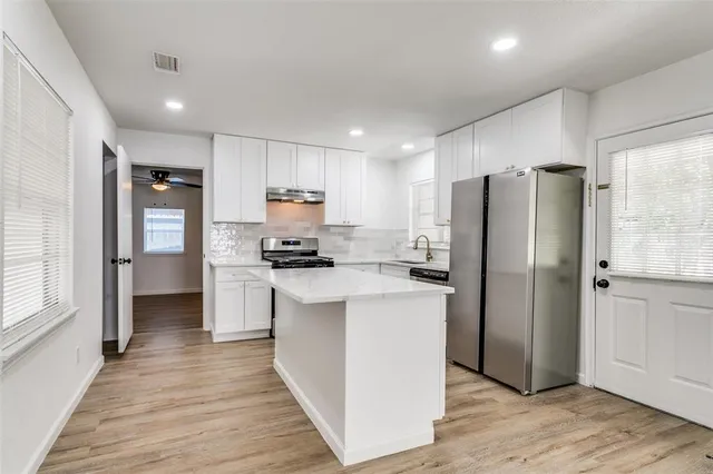 a kitchen with kitchen island wooden cabinets a refrigerator sink and stove