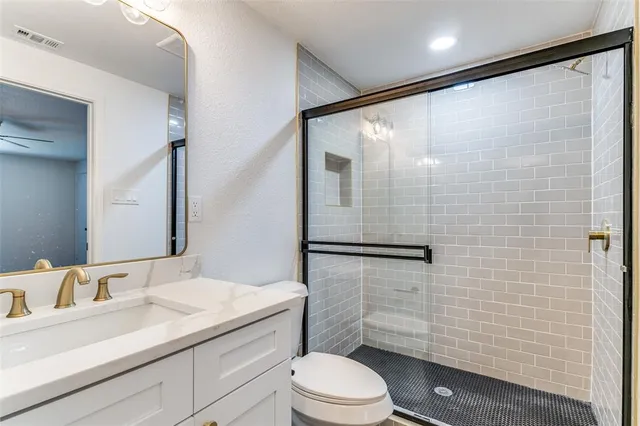 a bathroom with a sink a toilet a mirror and shower