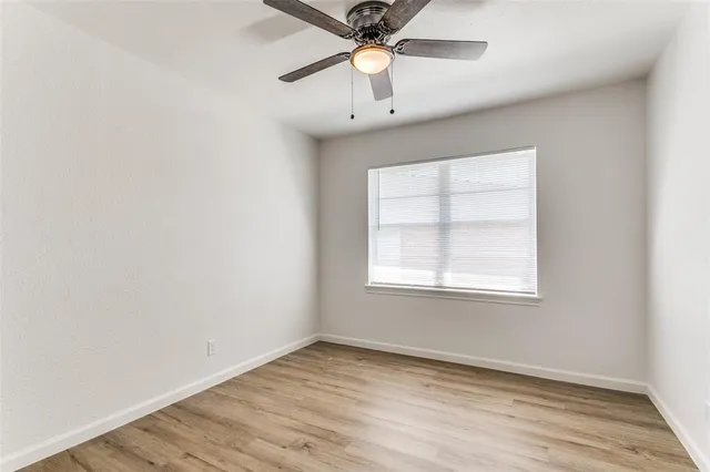 an empty room with a window and a chandelier fan