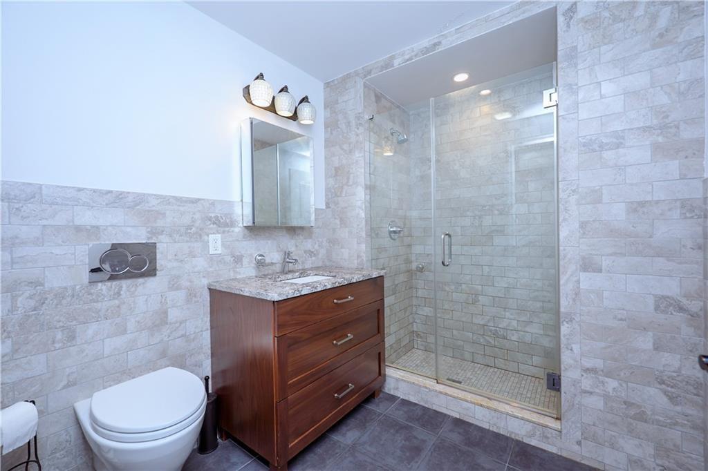 7819 Bay Parkway, Unit PH Brooklyn, NY 11214 - Photo 13 of 28 a bathroom with a toilet a sink and mirror