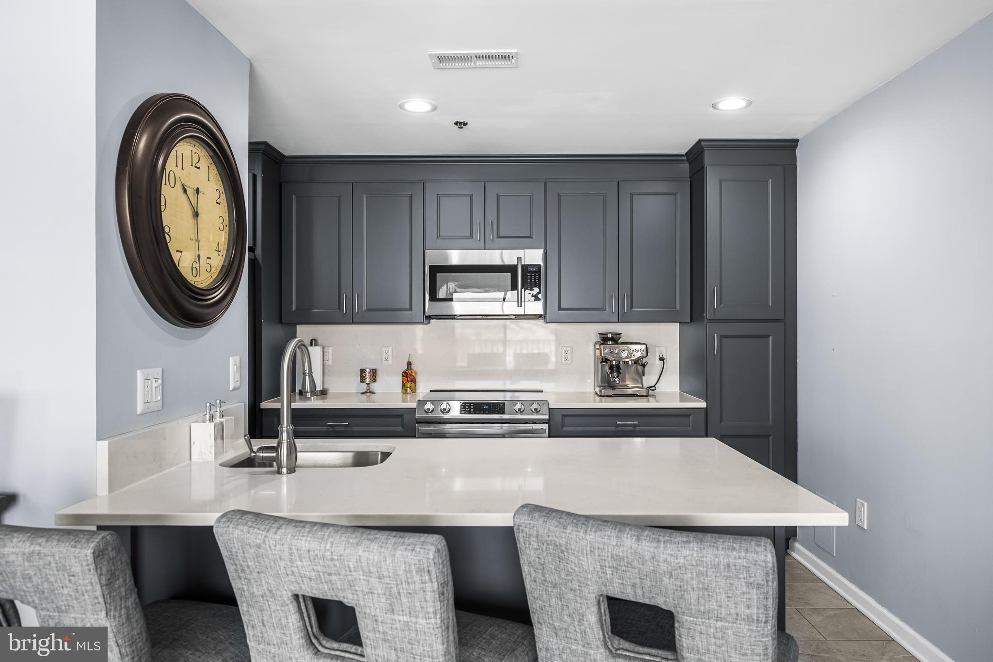2702 Lighthouse Point East, Unit 720 Baltimore, MD 21224 - Photo 9 of 37 a kitchen with kitchen island granite countertop a stove top oven a sink and dishwasher