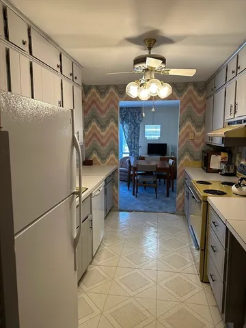 a kitchen with stainless steel appliances granite countertop a refrigerator a sink dishwasher a dining table and chairs with wooden floor