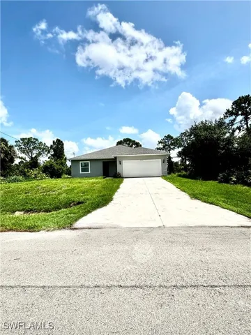 a view of a white house with a yard and potted plants